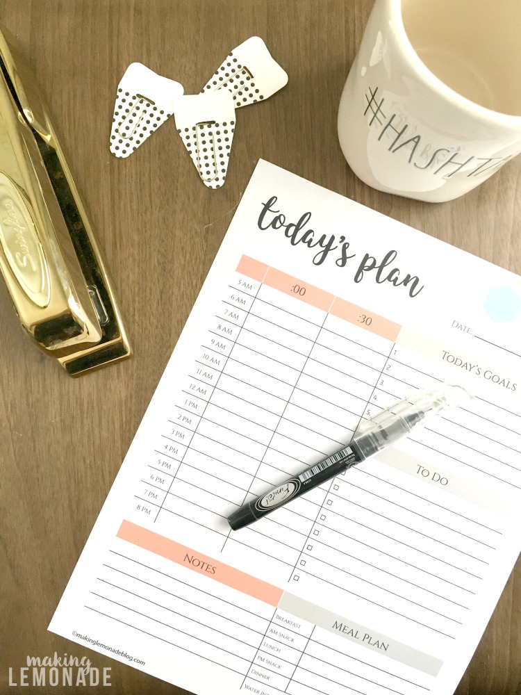 Daily planner on wooden counter with mug and pen