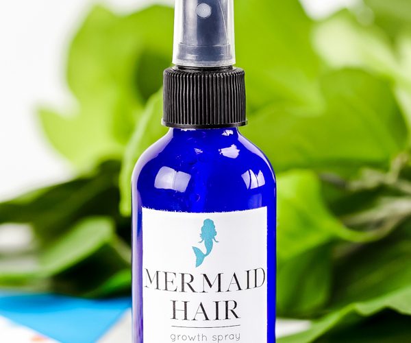 blue glass bottle with mermaid hair spray label on it