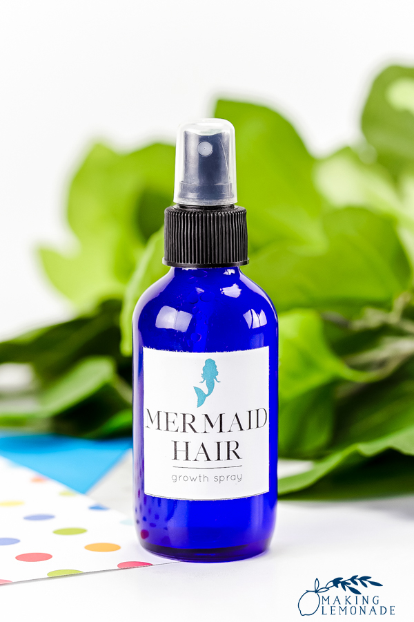 blue glass bottle with mermaid hair spray label on it