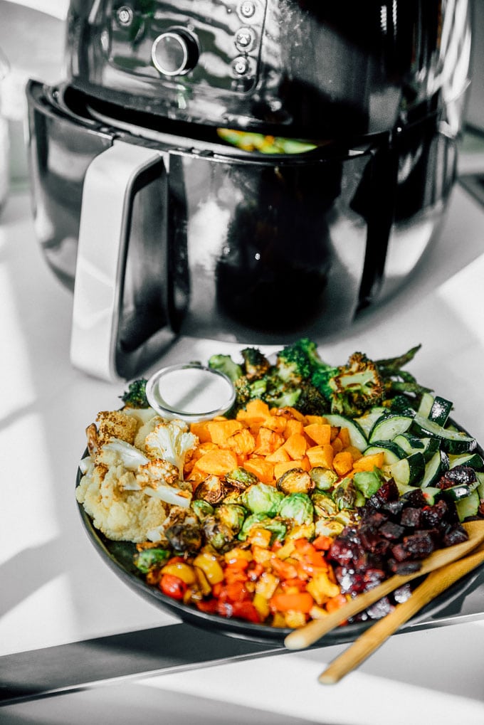 plate of various vegetables and a white dipping sauce with an air fryer in the background
