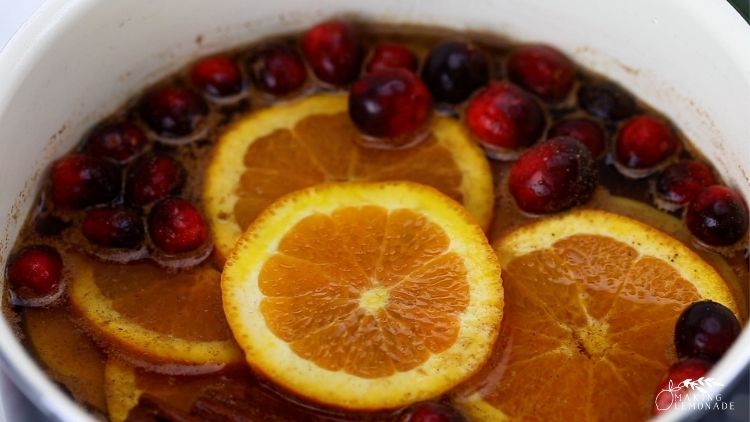 A saucepan with cranberries and orange slices in it 