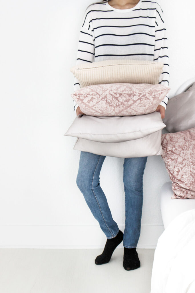 woman holiding stack of pillows