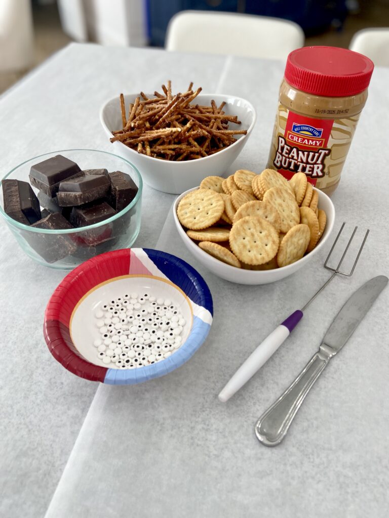 ingredients for Halloween Spider Treats: Ritz crackers, pretzel sticks, chocolate, peanut butter and candy eyes