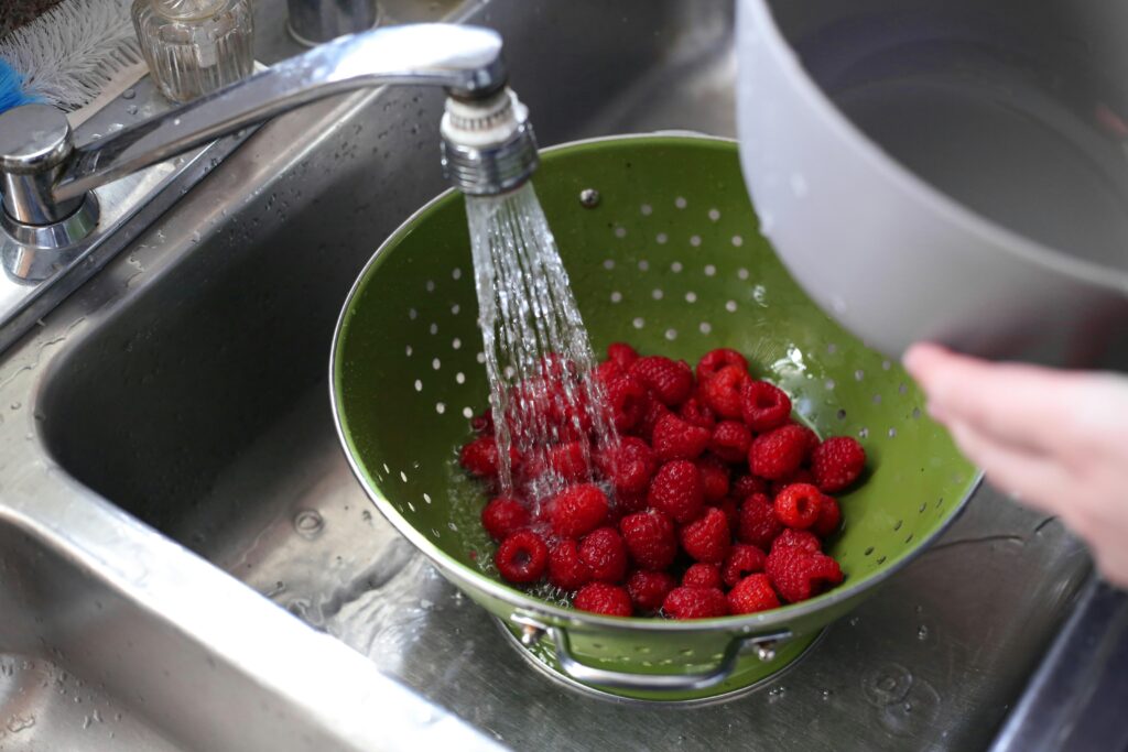 washing raspberries in a colander