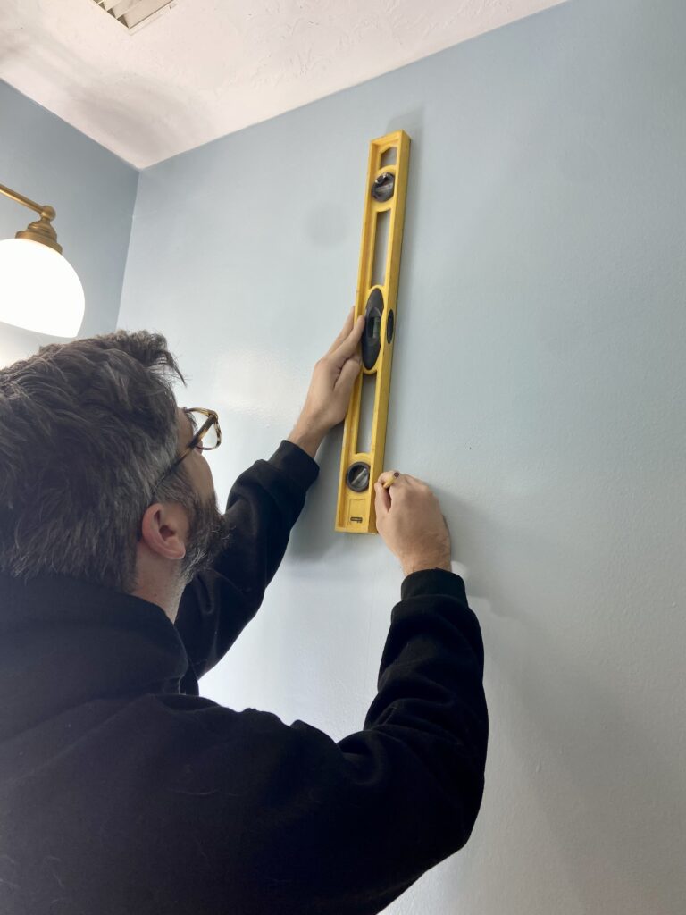 measuring for the first piece for the install peel-and-stick wallpaper