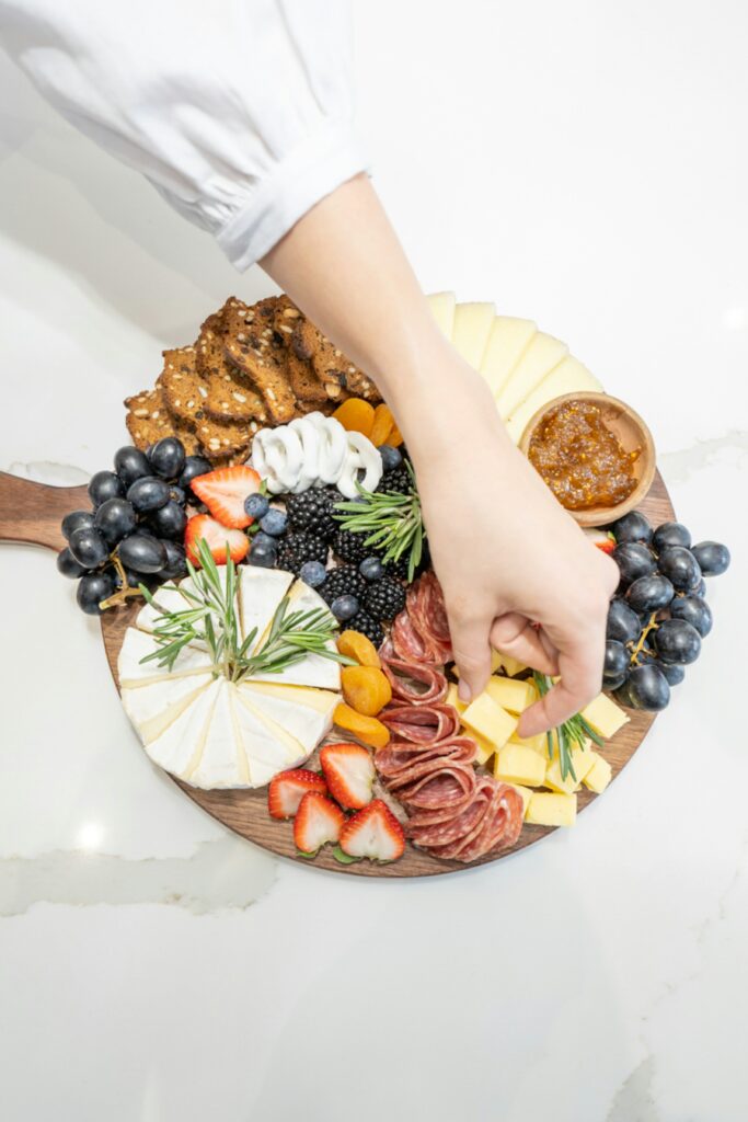 charcuterie board and hand taking cheese