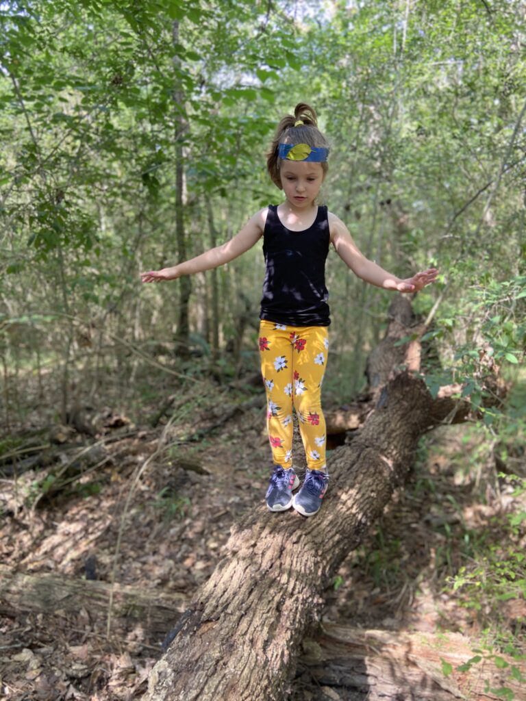 preschooler balancing on a log in nature