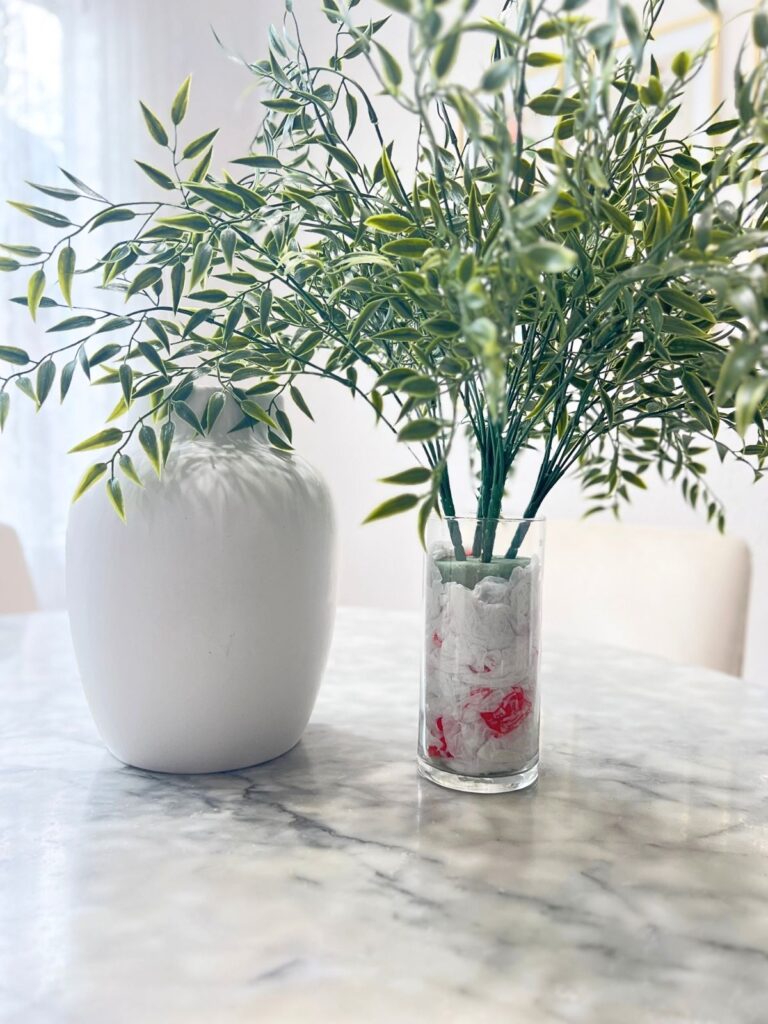 arranging artificial flowers with grocery bags in inner vase to increase the height of the stems