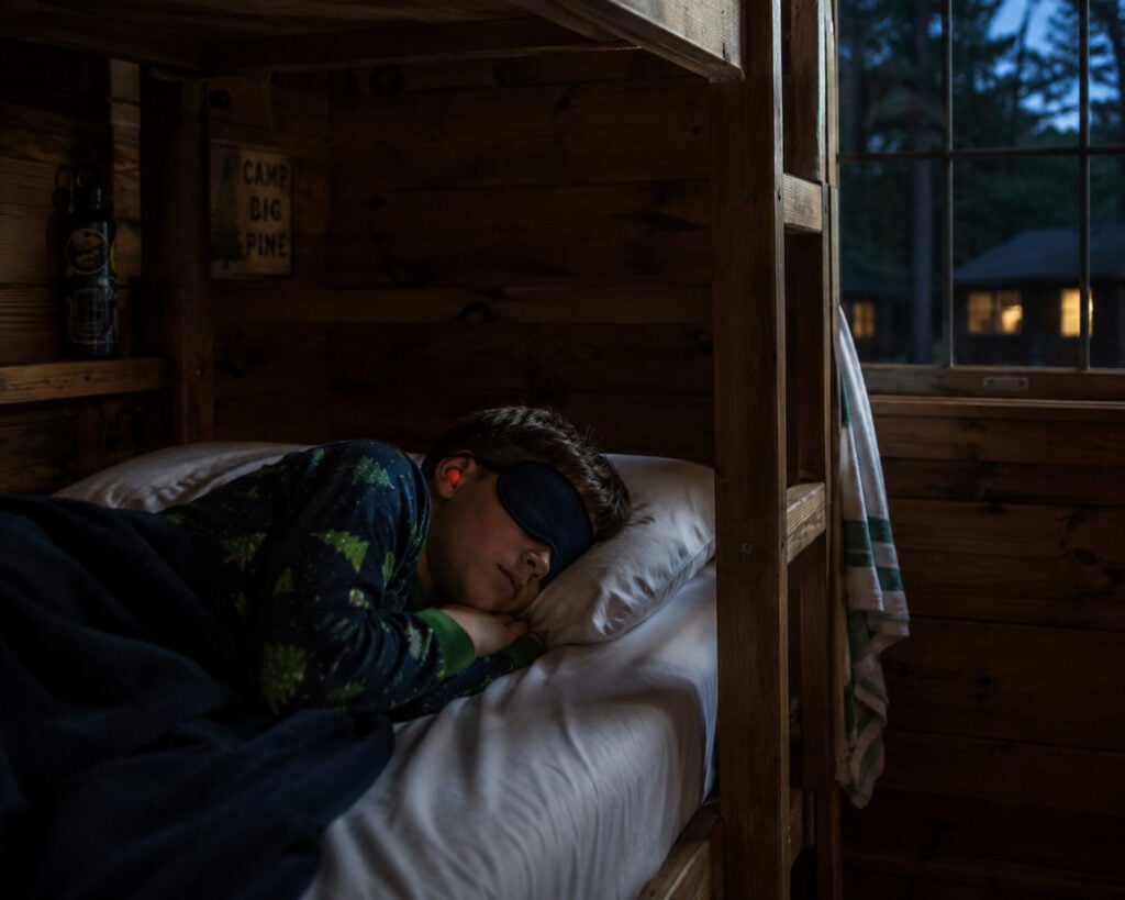 boy at summer camp with eye mask and ear plugs